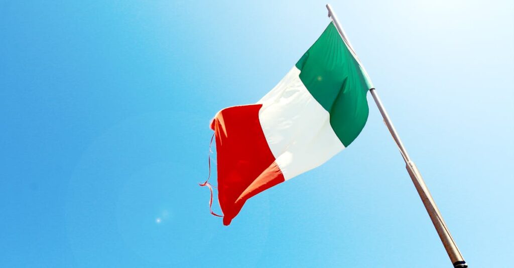Vivid image of the Italian flag waving on a flagpole against a bright blue sky.