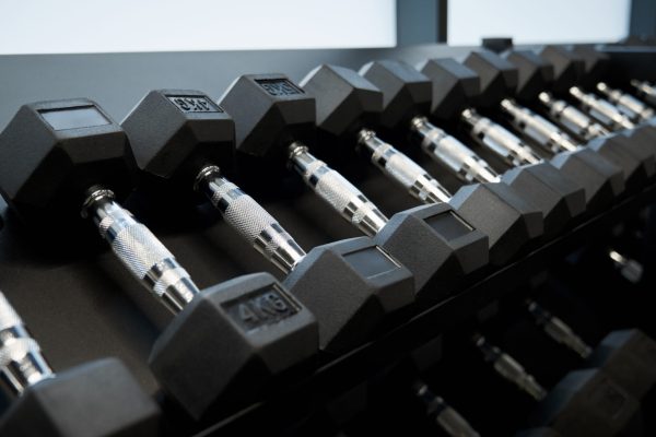 Close up of black dumbbells different weight on shelf in modern gym. Concept of special sports equipment for exercise and for improving body.