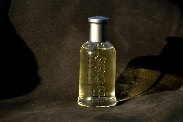 Sophisticated perfume bottle with embossed text elegantly showcased on dark fabric backdrop.