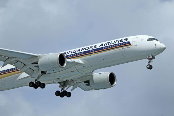 A close-up view of a Singapore Airlines airplane flying against a cloudy sky.