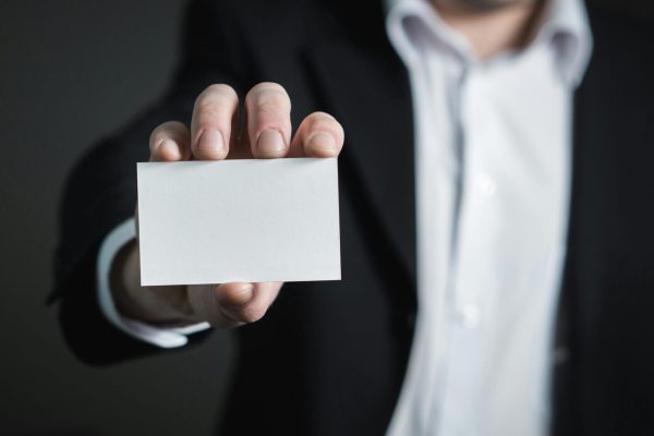 A man in a suit presenting a blank business card for corporate usage.