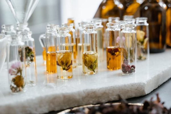 Close-up of various aromatic floral oils in glass bottles, showcasing their vibrant colors and natural ingredients.